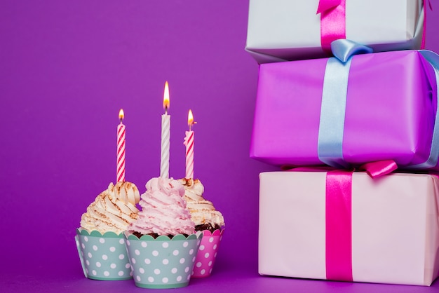 Cupcakes with lit candle next to presents