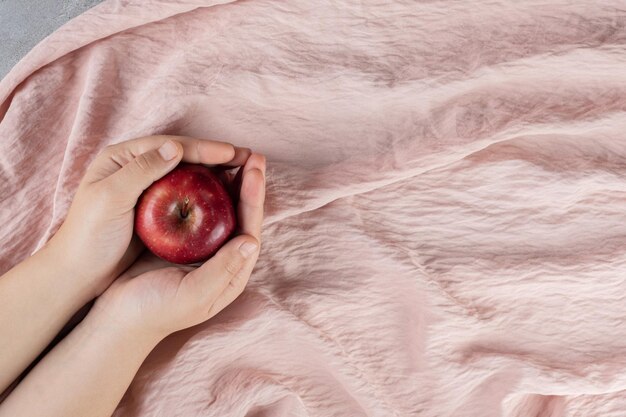 Cupped hands holding a single apple on textile surface