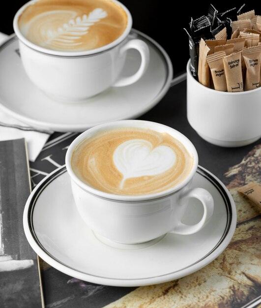 Cups of cappuccino with heart and rosetta latte art