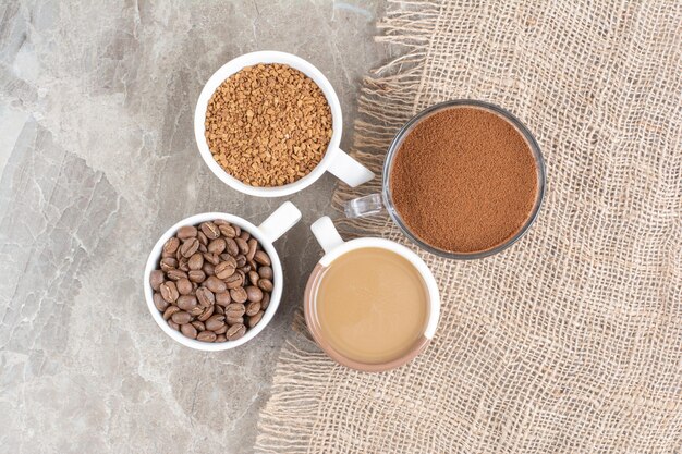 Cups of coffee, coffee beans and ground coffee on marble surface. High quality photo