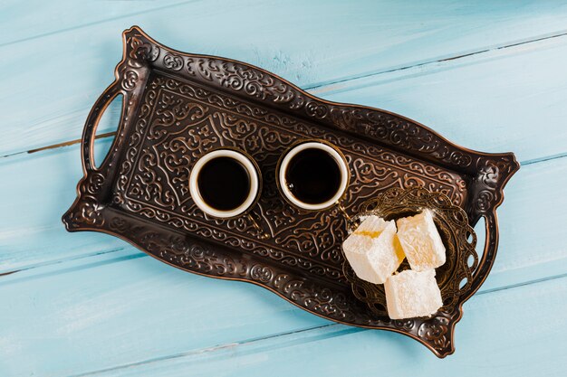 Cups of coffee near saucer with sweet Turkish delights on tray