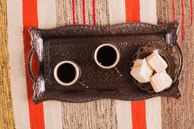 Cups of coffee near saucer with sweet Turkish delights on tray