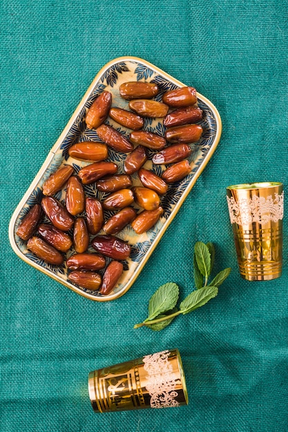 Free photo cups near plant twig and dried fruits on tray