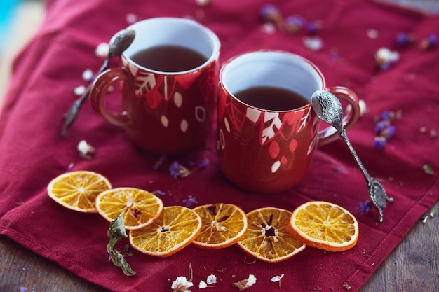 The cups of tea and pieces of mandarins stand on the table