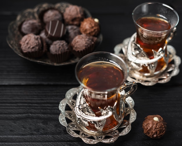 Cups of tea with truffles and wooden background