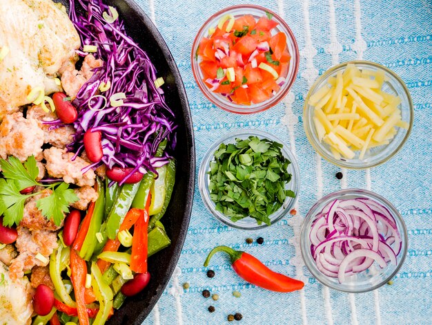 Cups of vegetables near Mexican dish