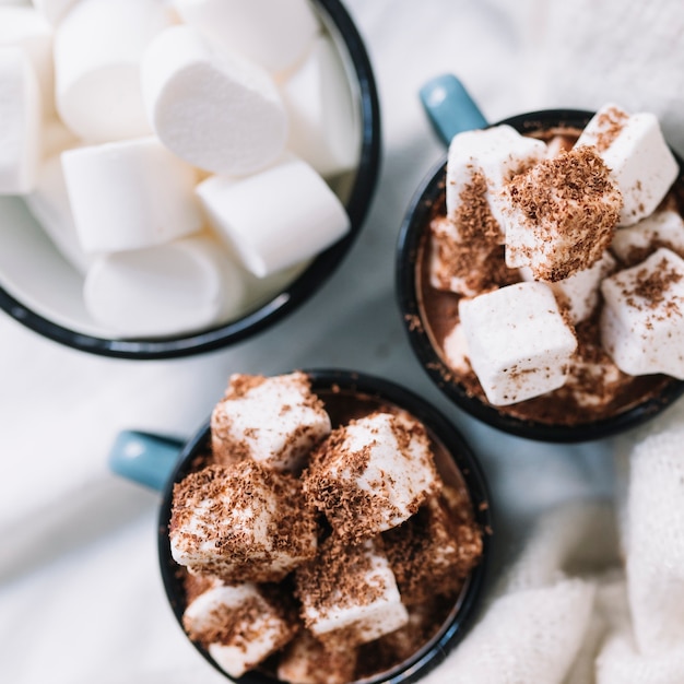 Cups with marshmallows and cocoa powder on table 