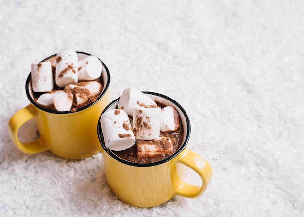 Free photo cups with marshmallows between snow