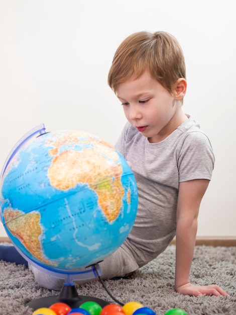 Curious boy looking on an earth globe