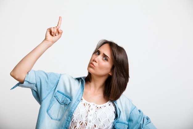 Curious enthusiastic woman pointing up