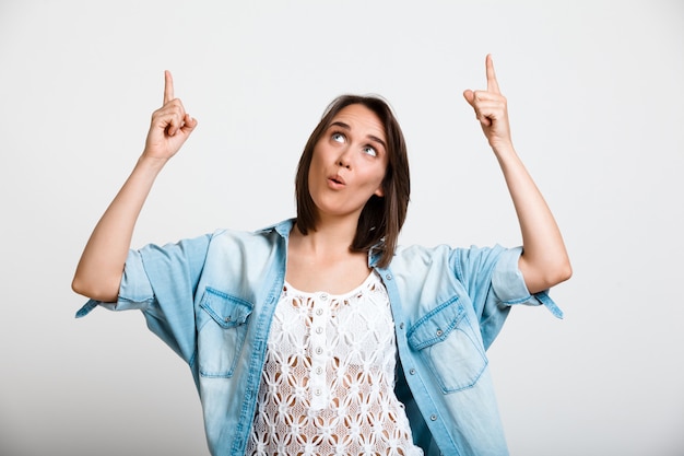 Curious enthusiastic woman pointing up