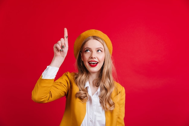Curious french woman pointing with finger up.  refined stylish girl in yellow beret.