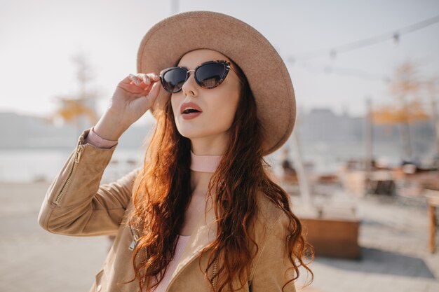 Curious ginger woman touching her sunglasses