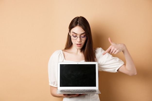 Curious girl in glasses pointing at laptop screen check out online deal demonstrate project on compu...