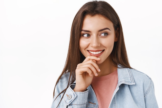 Donna moderna affascinante e curiosa in giacca di jeans, guarda qualcosa di allettante e divertente