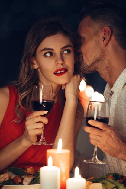 Curious lady in dress red with glass of wine listening her handsome man
