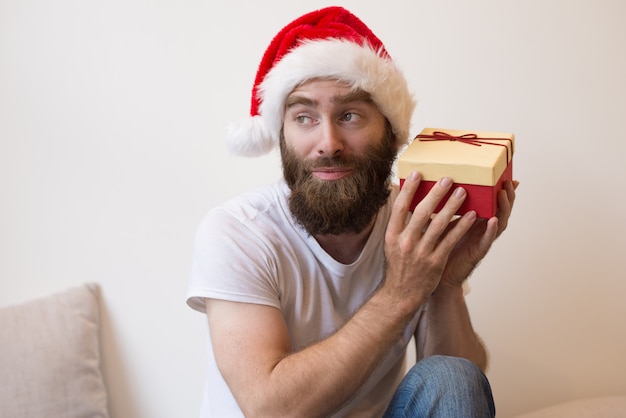 Curious man trying to guess what is inside Christmas gift box