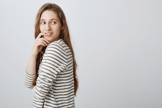 Curious young girl looking behind with tempting smile