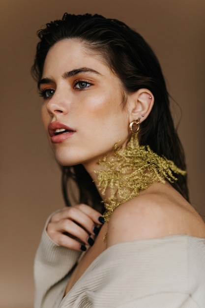 Curious young lady with shiny makeup. magnificent girl holding green leaf