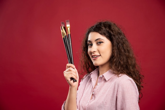 Curly artist holding paintbrushes.