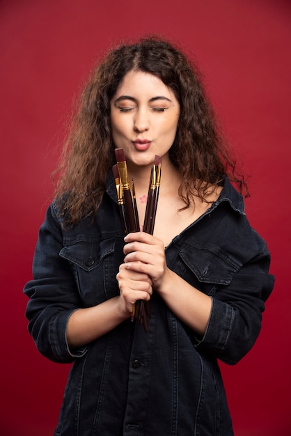Curly artist trying to kiss paintbrushes.