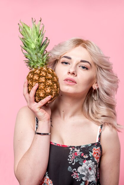 Curly attractive woman holding pineapple in hand 