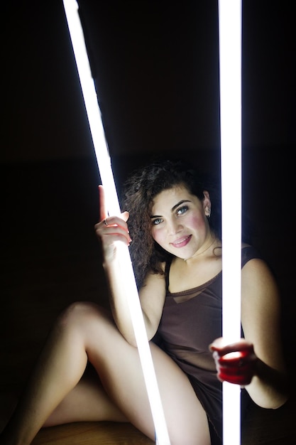 Bruna riccia modello taglie forti con due lunghe lampade a led in camera nera