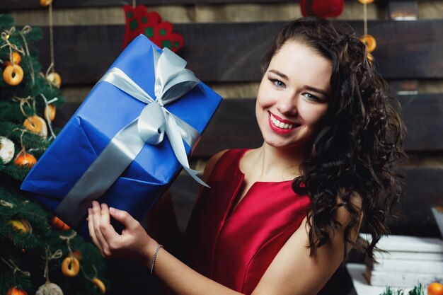 Curly brunette woman holds blue present box