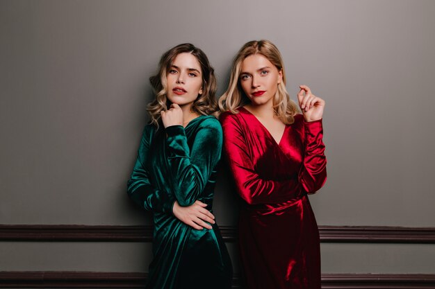 Кудрявая кавказская модель в зеленом платье. Комнатный портрет двух взрослых сестер в бархатных нарядах.