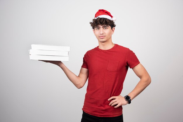 curly deliveryman in santa hat holding pizza boxes.
