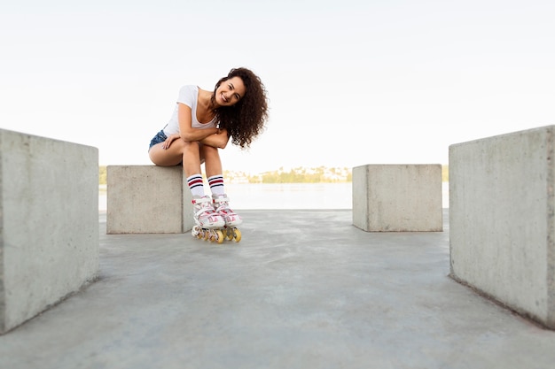 Curly girl posing while wearing rollerblades with copy space