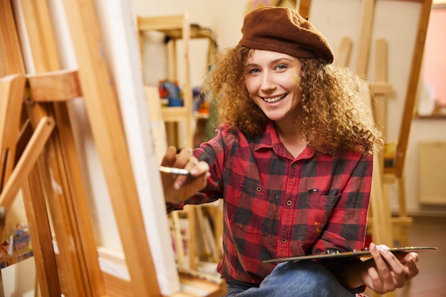 Curly girl with adorable smile draws a painting