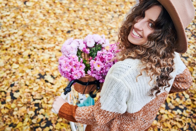 Free photo curly girl with bicycle on background of fallen leaves