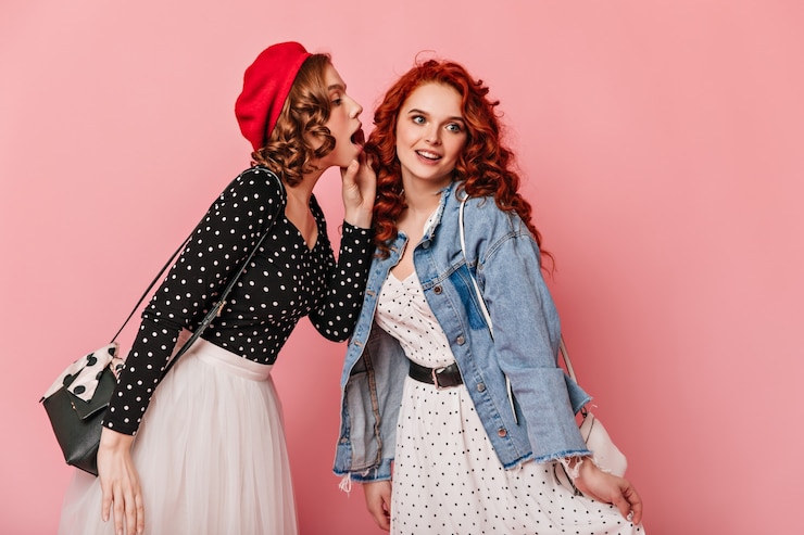 Free Photo curly girls in casual outfit talking on pink background. studio shot of refined friends sharing rumours.