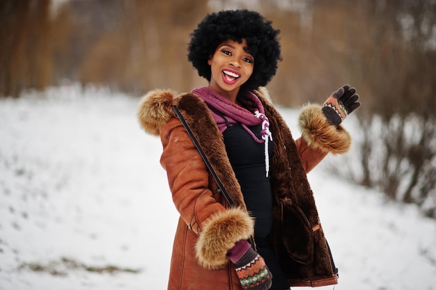Curly hair african american woman wear on sheepskin coat and gloves posed at winter day