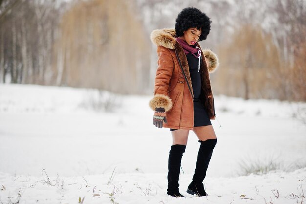 Curly hair african american woman wear on sheepskin coat and gloves posed at winter day
