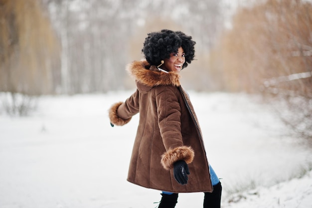 곱슬머리 아프리카계 미국인 여성은 겨울날 양가죽 코트와 장갑을 낀다