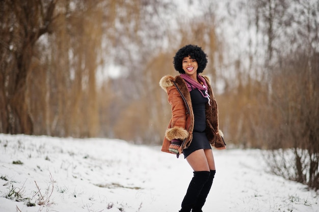 Curly hair african american woman wear on sheepskin coat and gloves posed at winter day