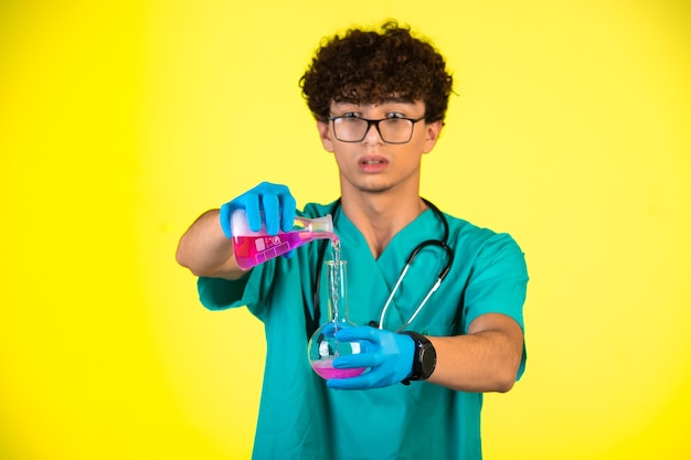 Curly hair boy in medical uniform and hand masks doing chemical reaction