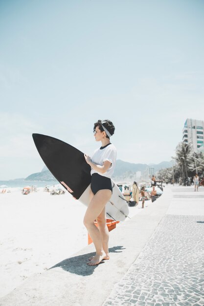 Вьющиеся волосы женщина держит доску для серфинга на пляже Рио-де-Жанейро