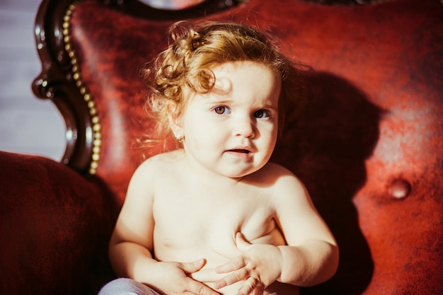 "Curly haired blonde toddler sitting in chair"
