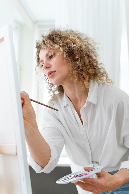 Curly-haired blonde woman painting at home