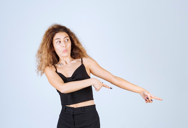 Free photo curly haired blondie girl pointing to the right.