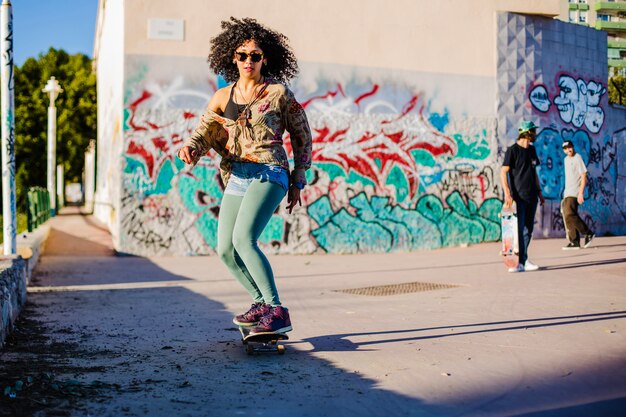 Curly haired brunette girl riding skateboard outside