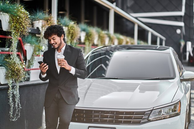 Curly-haired businessman from India drinks coffee.