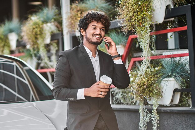 Curly-haired businessman smiles and talks on the phone.