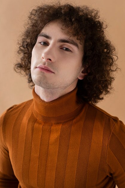 Curly haired man with brown blouse posing