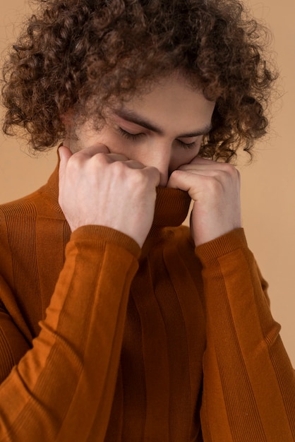 Curly haired man with brown blouse posing