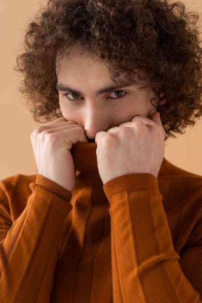 Curly haired man with brown blouse posing