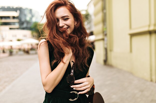 Curly lady smiling and walking through city